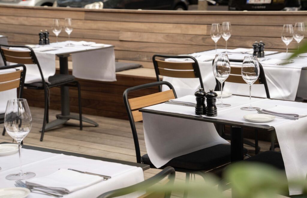 Restaurantterras met gedekte tafels Terras van een restaurant met gedekte tafels, witte tafellopers, wijnglazen en peper- en zoutmolens